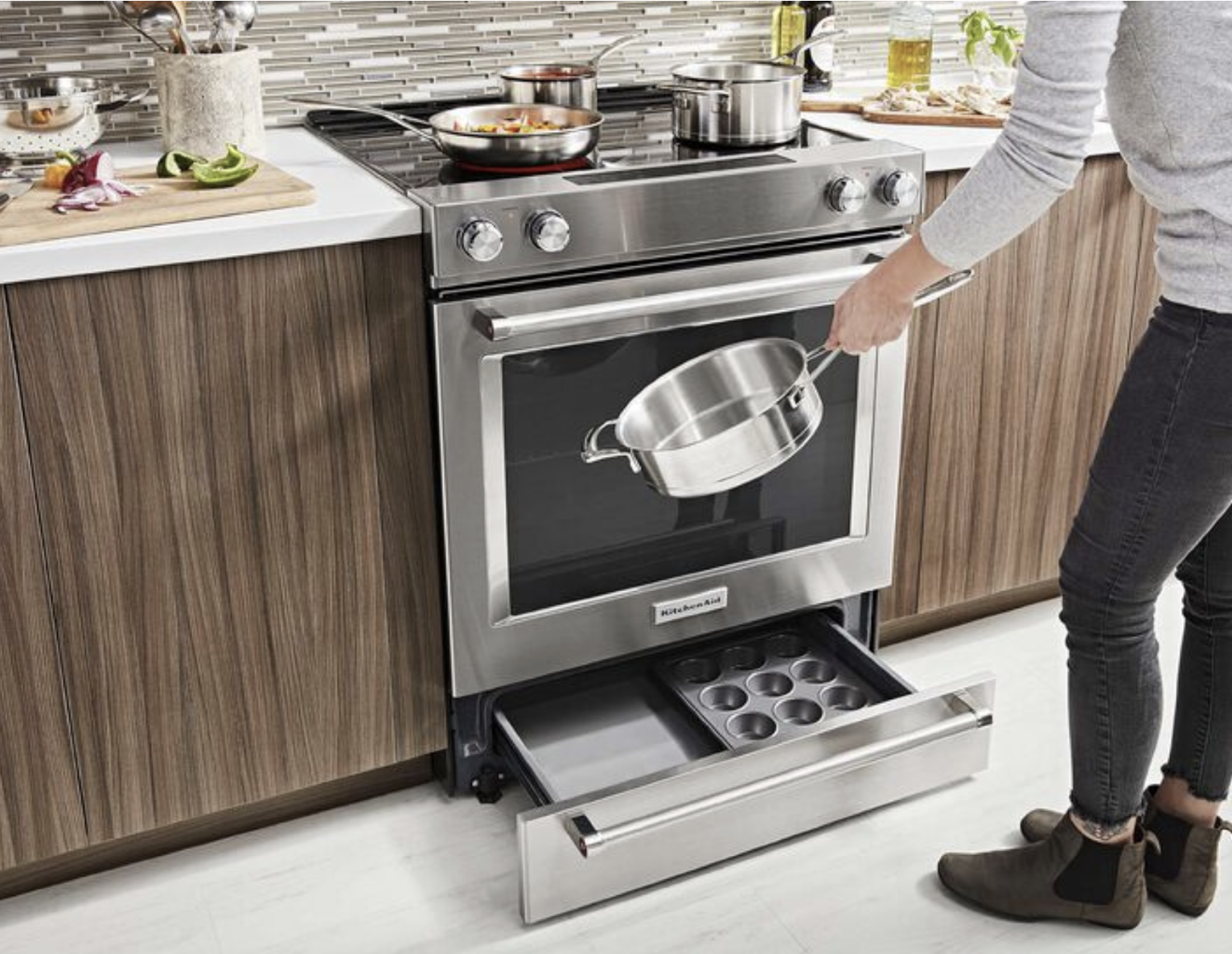 kitchenaid oven next to a kitchenaid dishwasher in a kitchen with lightwashed wooden cabinets